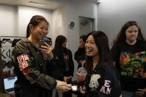 Two smiling females shaking hands at New York University's Club Fest.